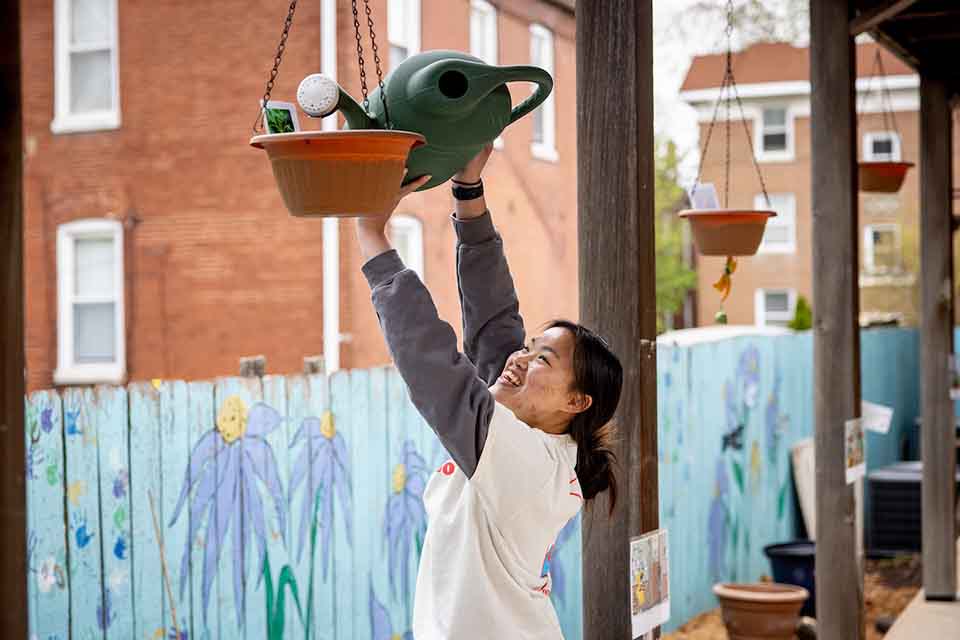SLU student volunteer SLU student volunteer watering a plant on a porch