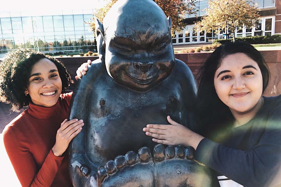 SLU Billiken Selfie Two students standing at Billiken statue