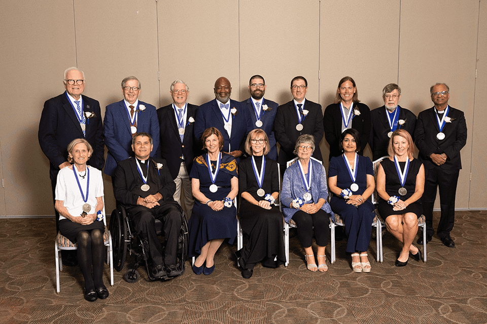 Alumni Merit Awardees 2024 A group of men and women wearing medals pose for a photo together.