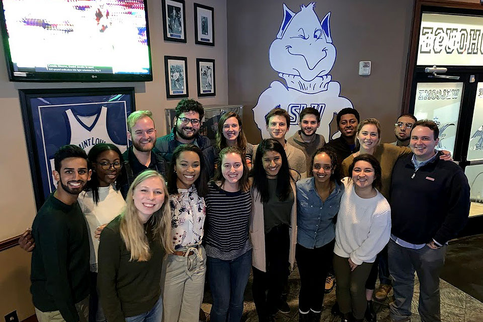 Spirit of the Billiken Class 2019 A group of students pose for a photo with a Billiken on the wall behind them.