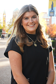 Charlotte Schoen A headshot photo of Charlotte Schoen with a clocktower and trees in the background.
