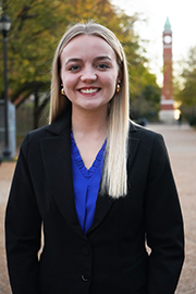 Claire Leingang A headshot photo of Claire Leingang with a clocktower and trees in the background.