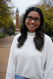Emily Tran A headshot photo of Emily Tran with a clocktower and trees in the background.