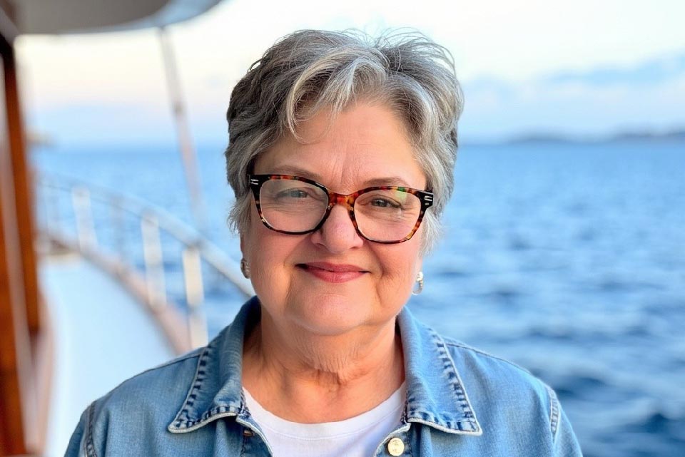 A woman poses for a photo with water behind her.