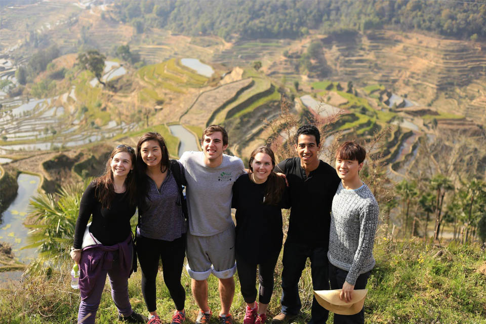 Study abroad in Beijing Students stand on a hillside overlooking a valley with terraced fields.