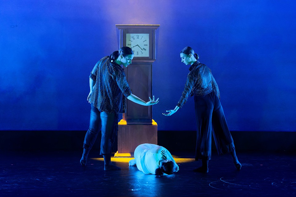 Three dancers stand in front of a clock Three dancers stand in front of a clock