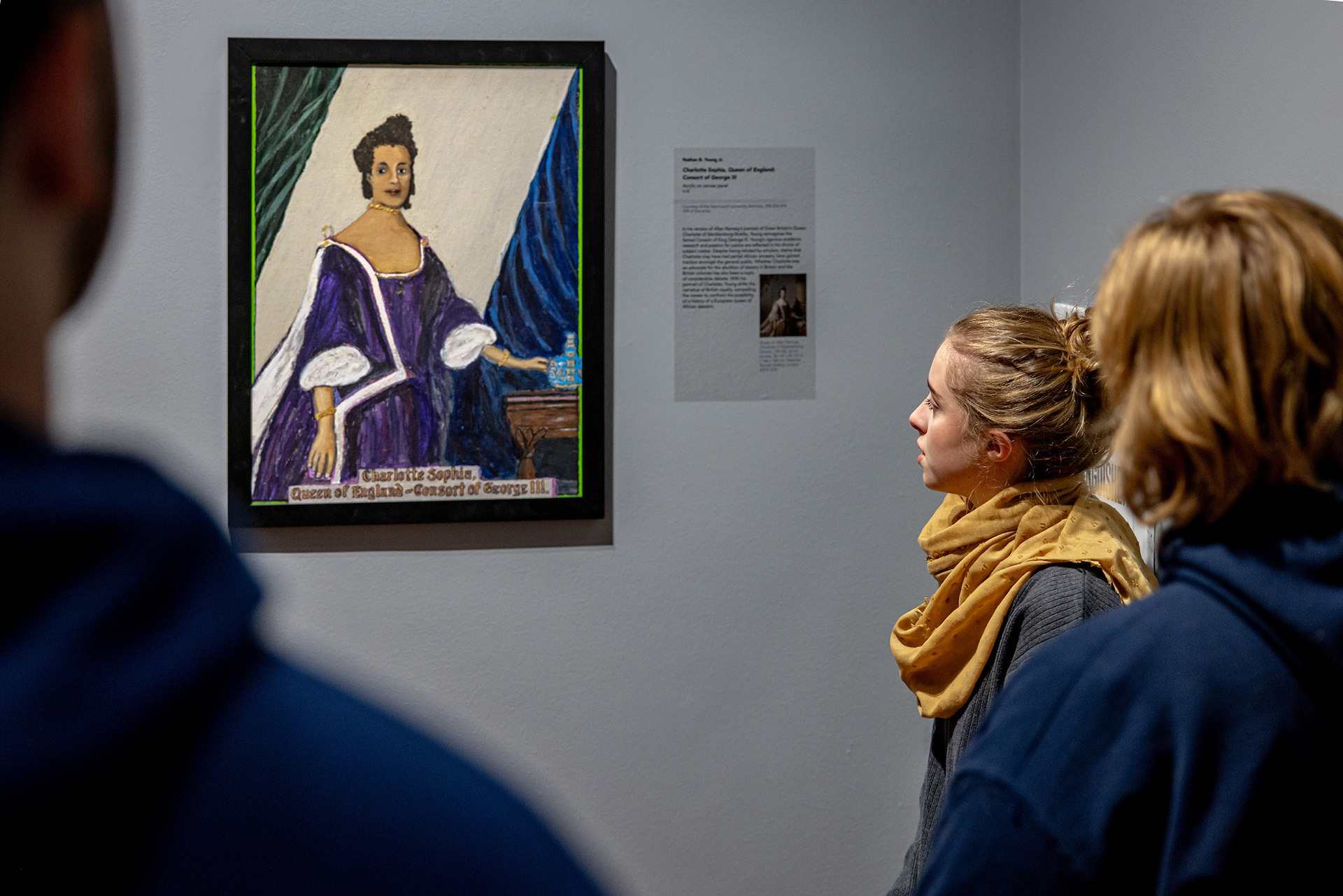 A blonde student in a yellow scarf studies a painting A blonde student in a yellow scarf studies a painting