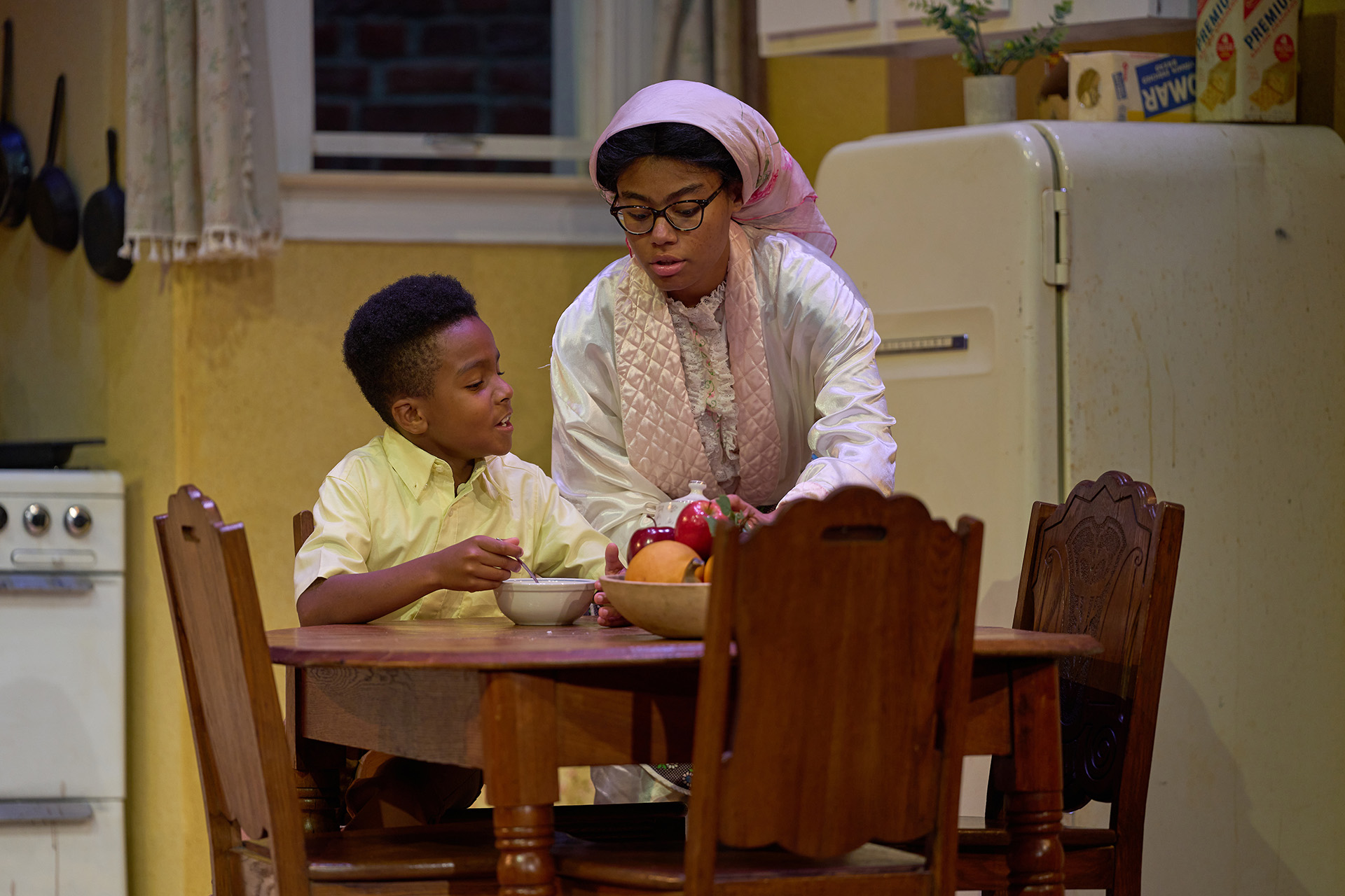 The SLU Theatre & Dance production of 'A Raisin in the Sun' directed by Kathryn Bentley, October 2024. A Black child and his mother sit at the breakfast table
