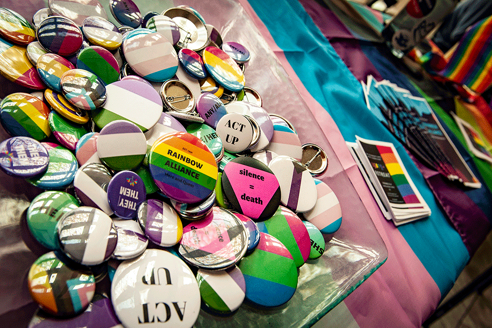 Buttons on a table LGBT pins and buttons spread out on a table covered with a flag