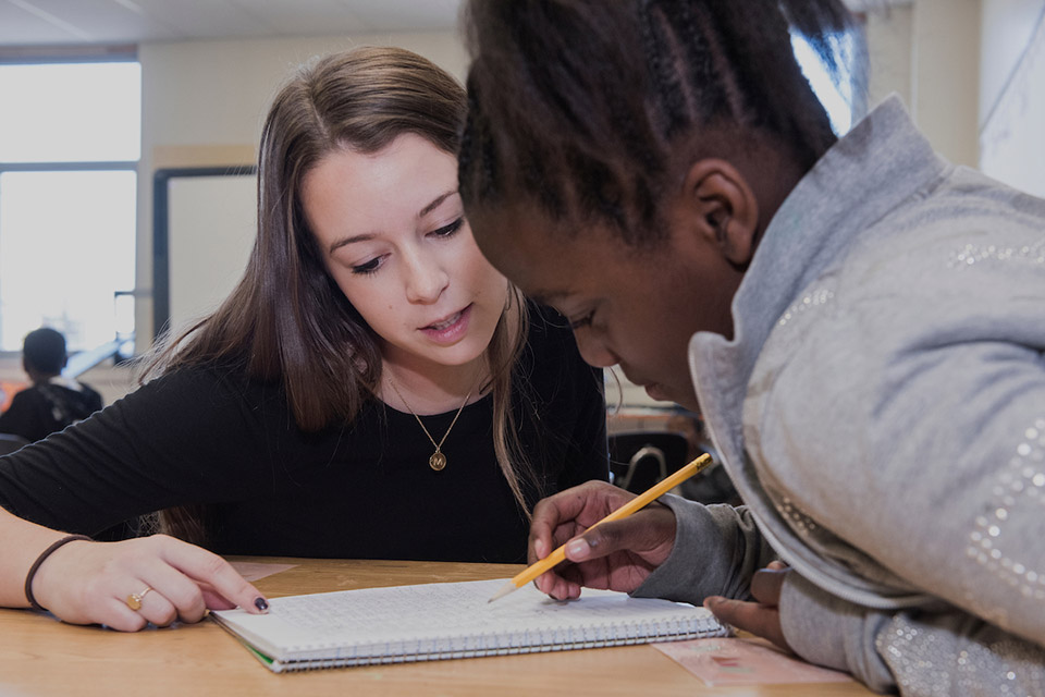 Bridge Program Two students look at a notebook while one hold a pencil.