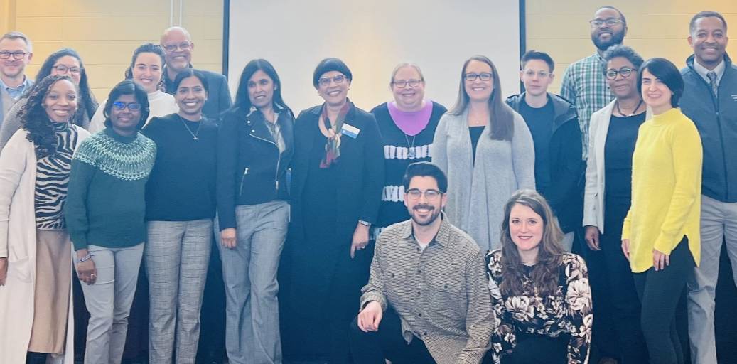 Faculty mentoring Participants line up in front of a whiteboard for a photo and smile.