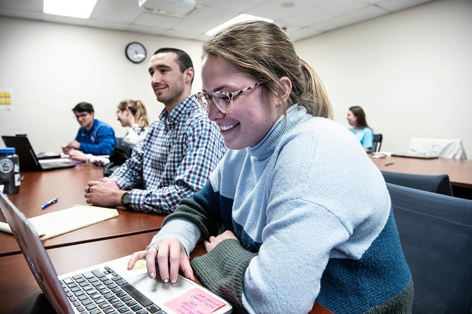 Services A student wearing glasses and a sweater works on her laptop in a graduate education course