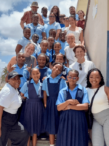 Belize Stairway SLU students and professors posing on a stairway with Belizean students and teachers. The Belizean students are wearing blue school uniforms.