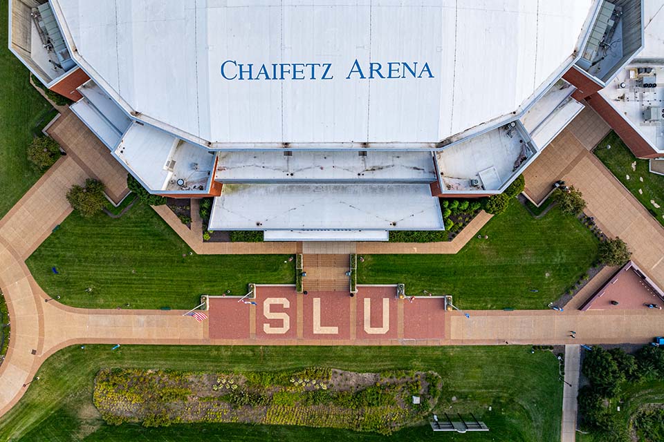 A view of Chaifetz Arena from above. Bricks on the path in front of the building spell out SLU.