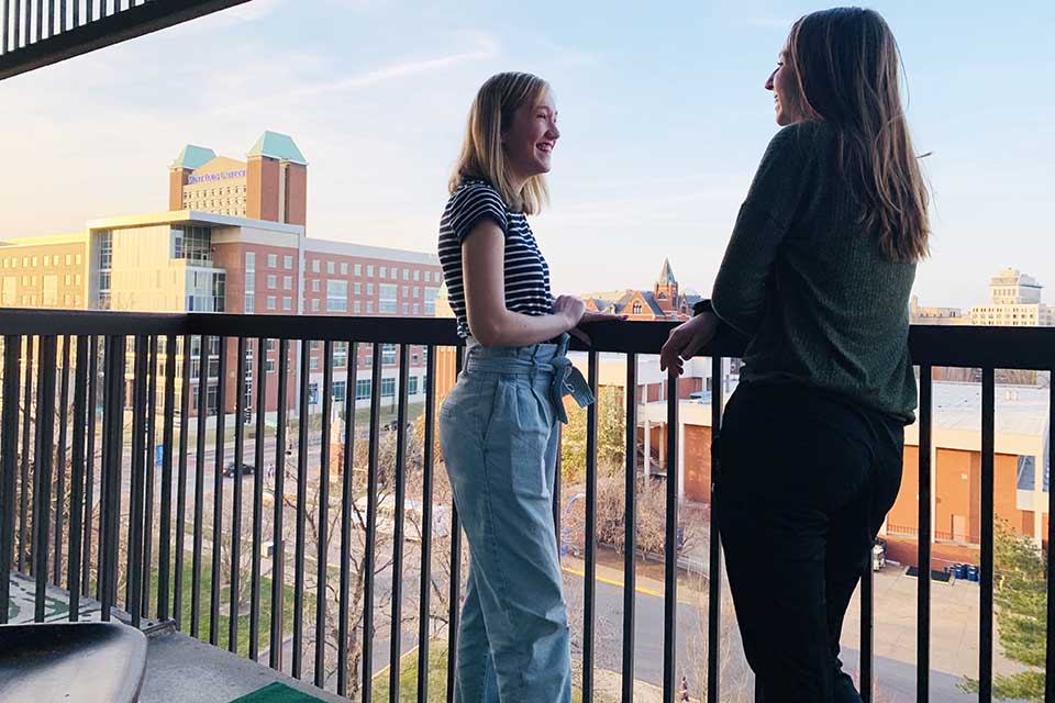 View from Marchetti Towers Two female students standing on a balcony overlooking campus