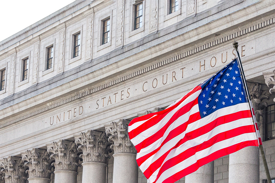 Photo of the United States Supreme Court building with a US flag waving in front of it Photo of the United States Supreme Court building with a flag waving in front of it