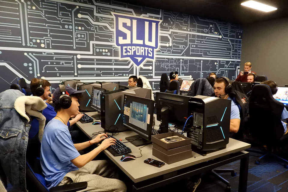 Esports Lab in the BSC Esports players at two tables with headphones and CPUs with the eports logo in the background