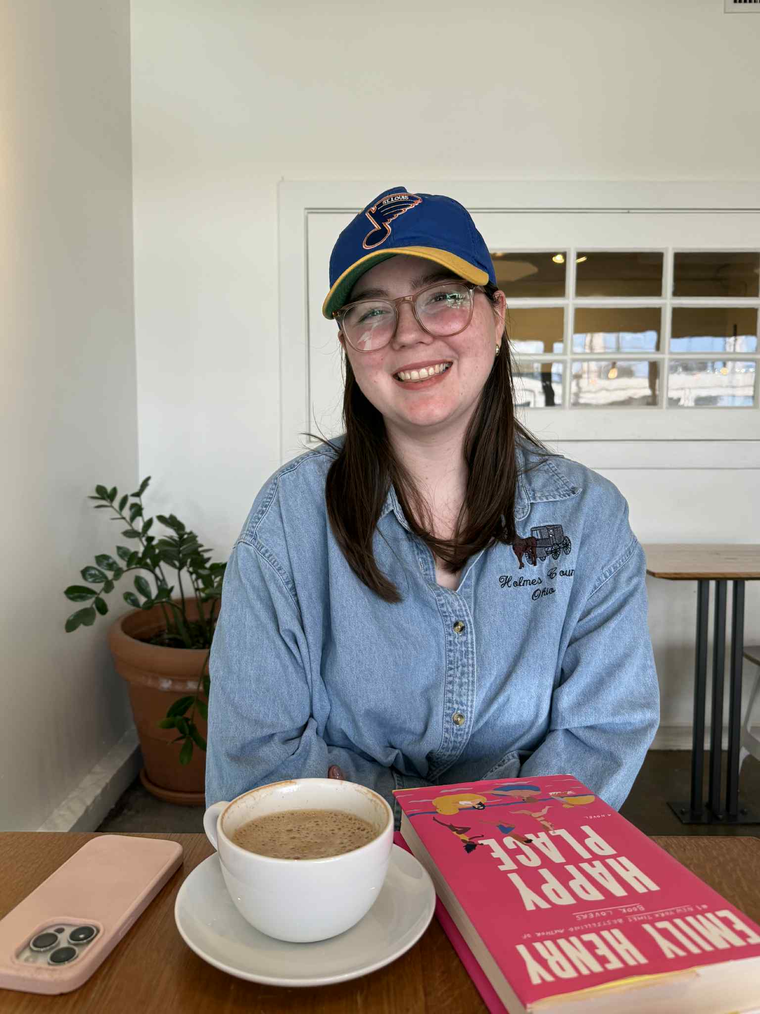 Julia Prodger Photo young woman, dark hair wearing a hat at a coffee shop
