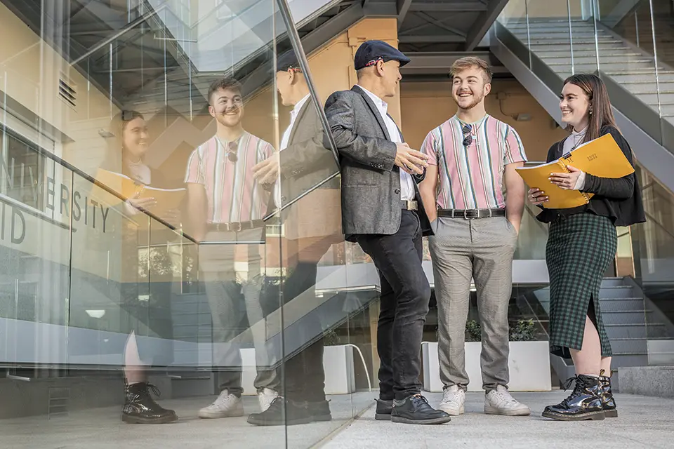 Political Science Two students talk with the professor outside of the classroom in Padre Rubio Hall.