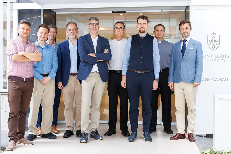 Participants at the International Workshop Science-Engaged Theology in the Catholic Tradition Nine individuals look at camera for group photo with building entrance in background.