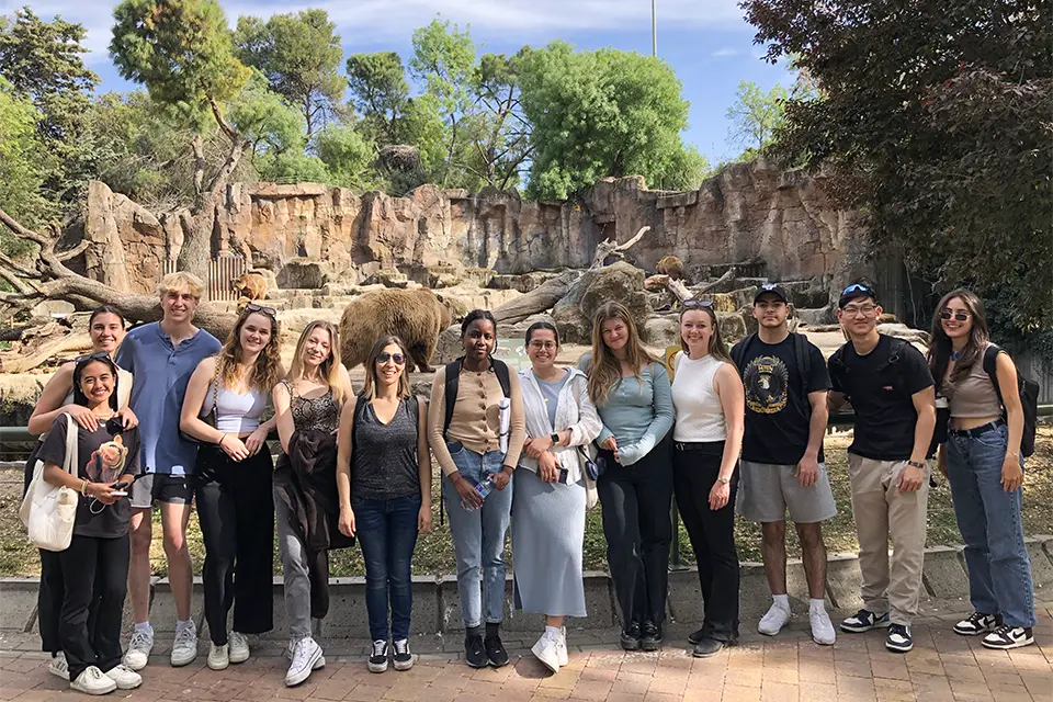 Madrid Zoo Students and professor stand in front of a rocky animal habitat with bears in the backround.l