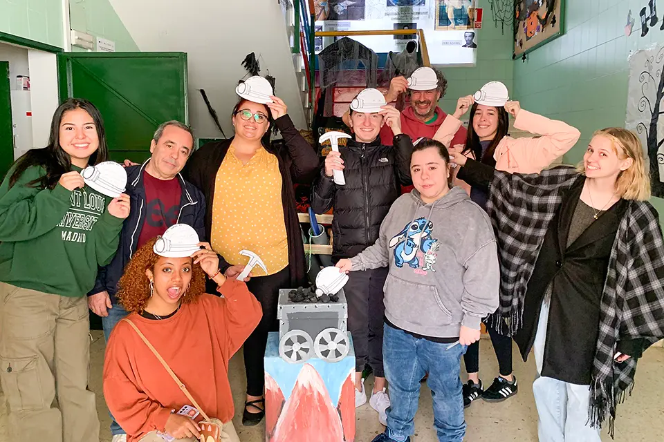 Field trip to Puertollano Students and a professor pose with cardboard cut outs of construction helmets and hammers.