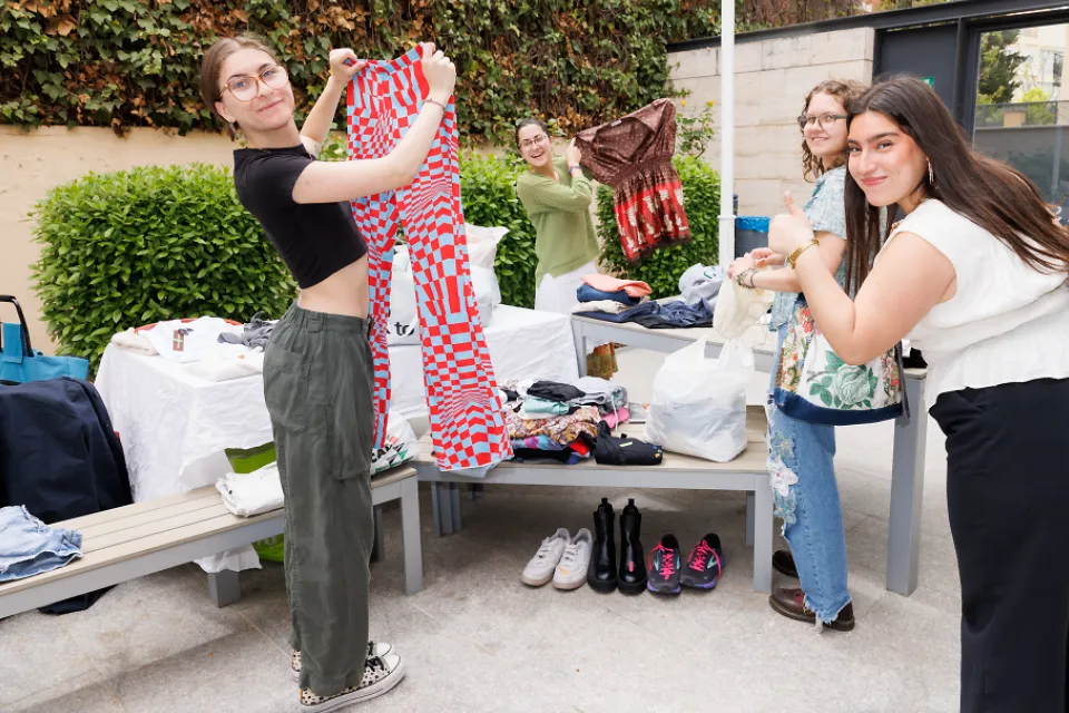 Student-led clubs Students hold up articles of clothing and another student gives a thumbs up while standing around a table filled with clothing and shoes.