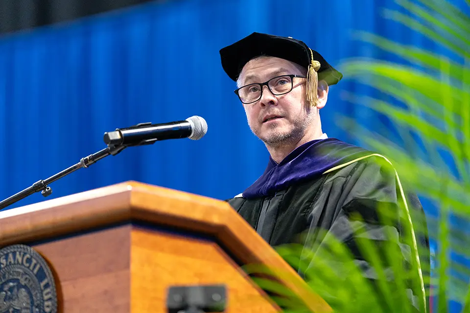 William Johnson, J.D. William Johnson on stage talking to the audience from a lectern with a microphone.