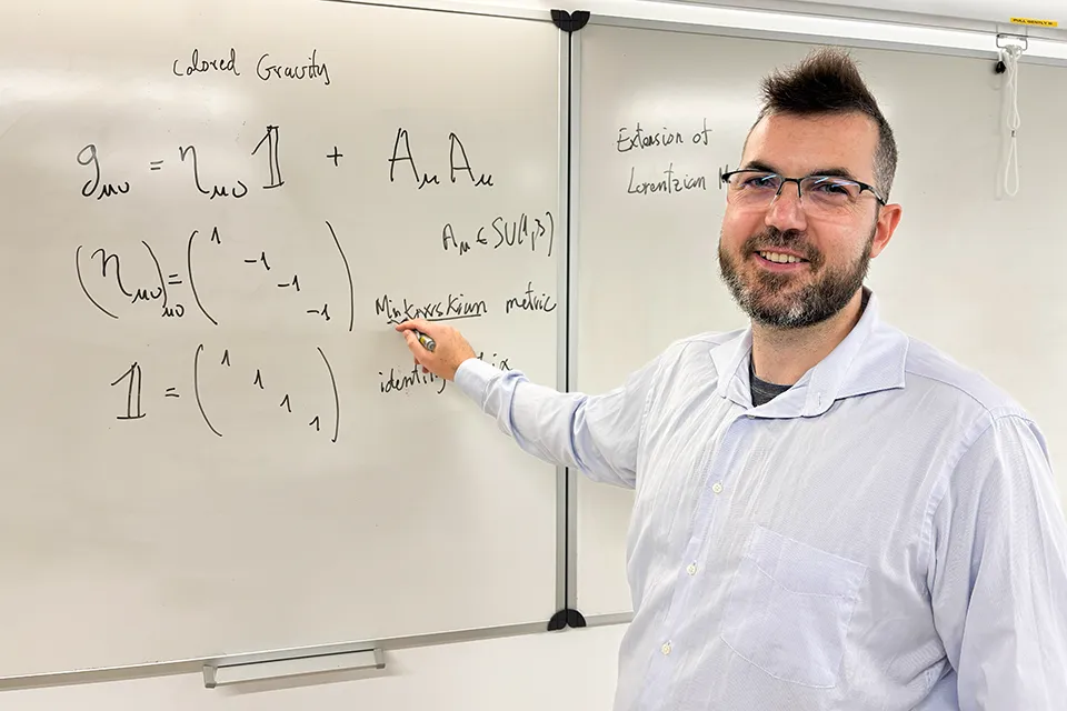 SLU-Madrid Mathematician Fills Gap in Einstein's Work Professor looks at camera while standing in front of a whiteboard with an equation written on it.