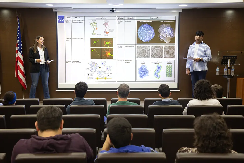 SLU-Madrid otorga su prestigioso premio en ciencia y tecnología Two students present with a PowerPoint projected in the background in an auditorium.