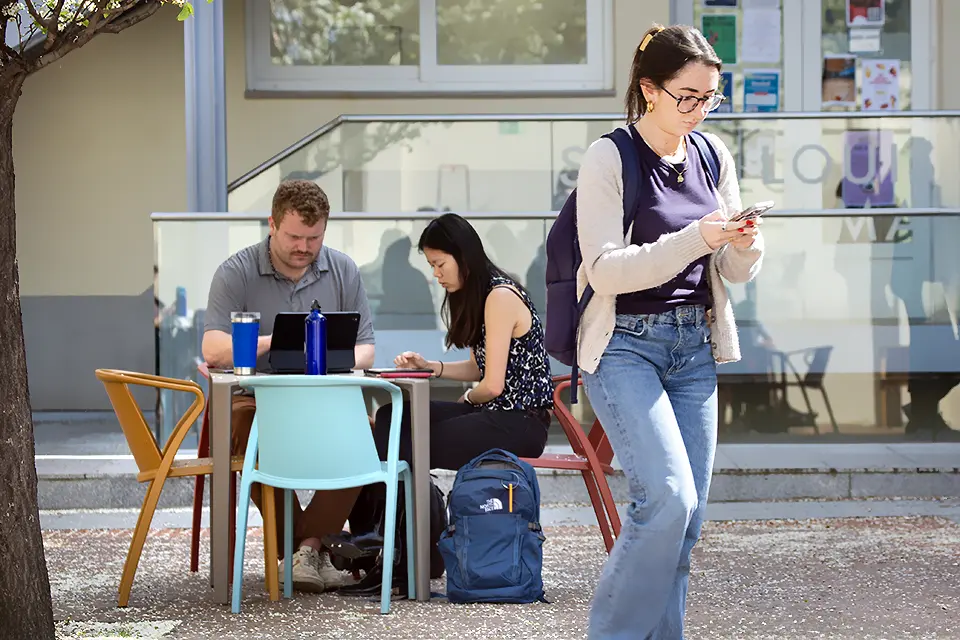 Students with a laptop looking at a phone in the patio of PRH. Students with a laptop looking at a phone in the patio of PRH.