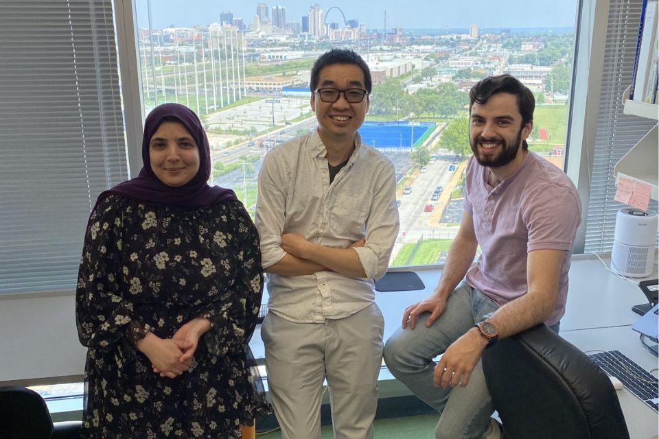 Researchers stand in front of a lab window with a view of the St. Louis skyline. Researchers stand in front of a lab window with a view of the St. Louis skyline.