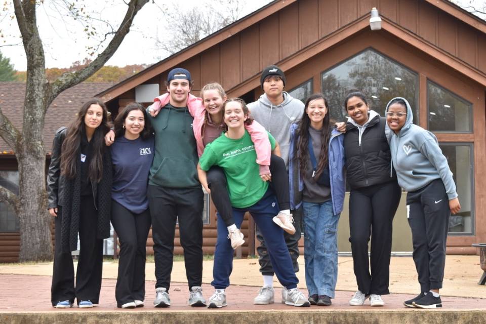 Micah Main photo A group of students pose for a photo outside of a retreat center in the woods.