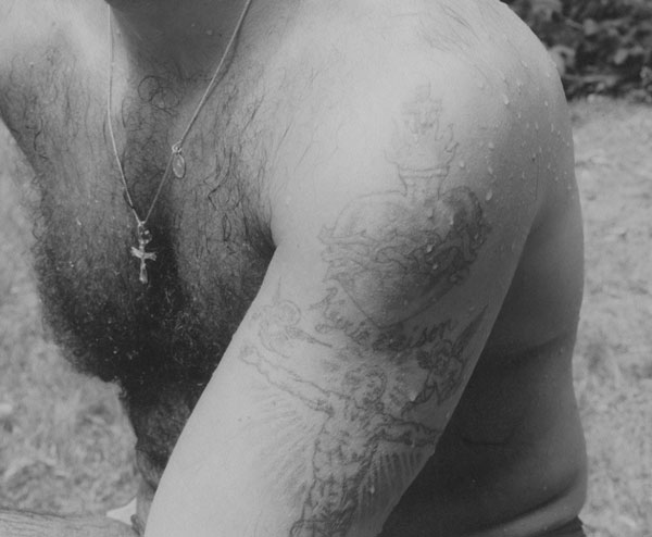 Adrian Kellard, Northport, NY, ca.1990. Photo by Regina DeLuise. Courtesy of the artist. A detail of a black-and-white photo of Adrian Kellard showing tatoos on his upper left arm.