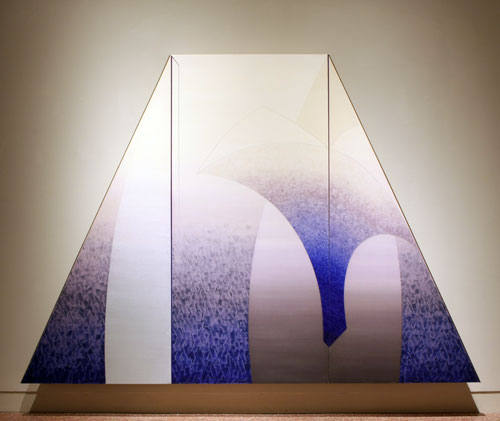 Daniel Ramirez, Caelestis Praesepe (Celestial Manger), 1989-90. Acrylic on canvas, aluminum, steel. MOCRA collection. Photo by Jeffrey Vaughn A painting by Daniel Ramirez titled Caelestis Praesepe (Celestial Manger). A large trapezoidal-shaped panting seems to hover off the wall. The abstract imagery includes arcing lines and gentle color gradients in purples and silvers, resulting in a sense of an architectural space like a gothic cathedral.