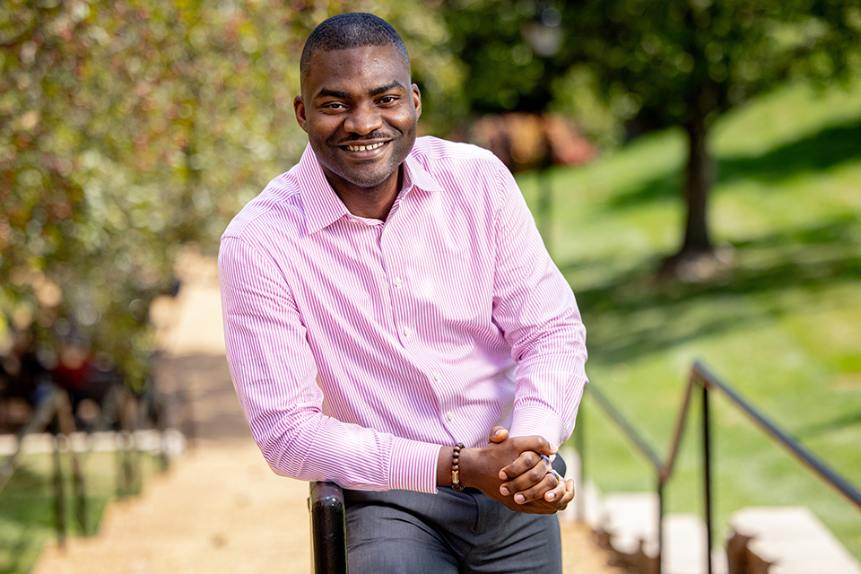 Olu Owoeye, Ph.D. Olu Owoeye, Ph.D., leans against a rail for a photo shot outdoors during the day.