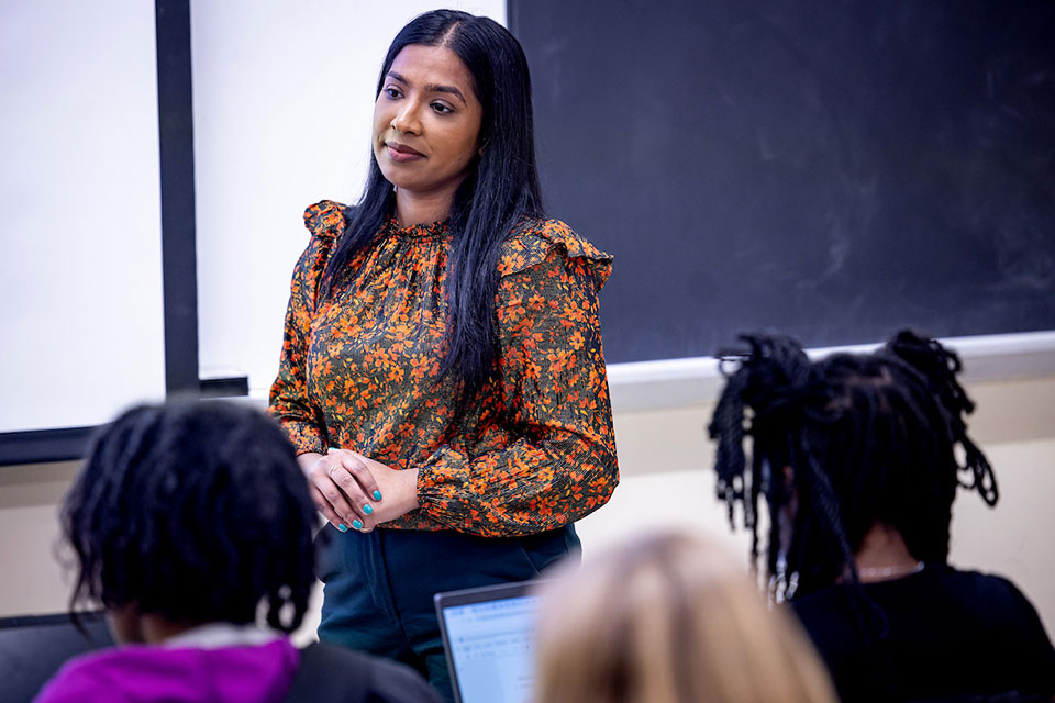 Professor Popy Begum, Ph.D., wearing a floral blouse, leads a classroom discussion. Students, some with laptops, focus on her. Professor Popy Begum, Ph.D., wearing a floral blouse, leads a classroom discussion. Students, some with laptops, focus on her.
