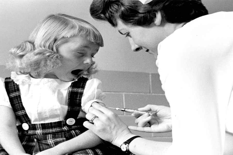 Cardinal Glennon In this black and white vintage image, a young girl makes a face as a nurse injects her with a shot.
