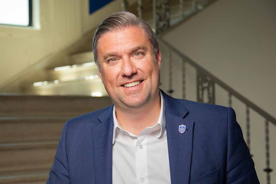 Troy A man in a suit stands on a staircase