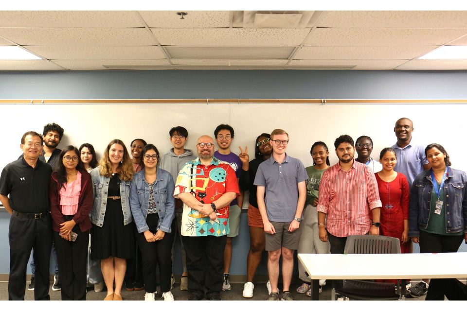 MCH Interest Group A group of approximately 20 students, faculty and staff interested in maternal child health stand, posing in front of a white board in a classroom.