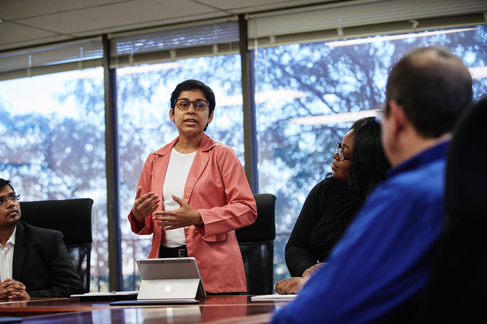 Public health students talking Students discuss their work with a professor in a conference room.