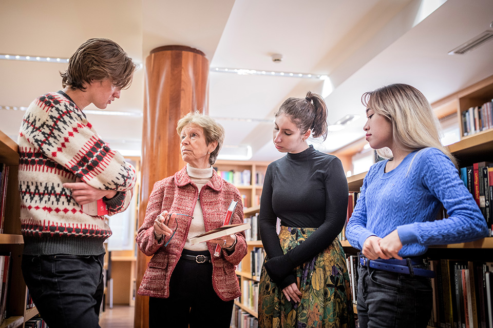 Encinar A professor discusses a book with students in a library