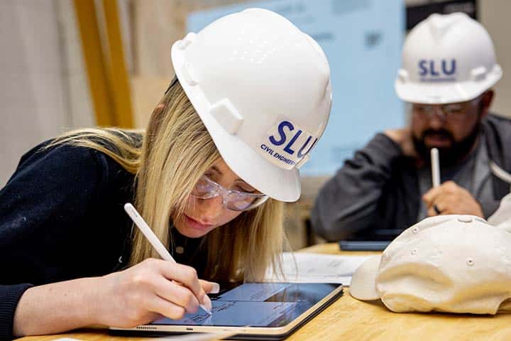 computer science class A student wearing a hardhat works on a tablet in a SLU classroom.