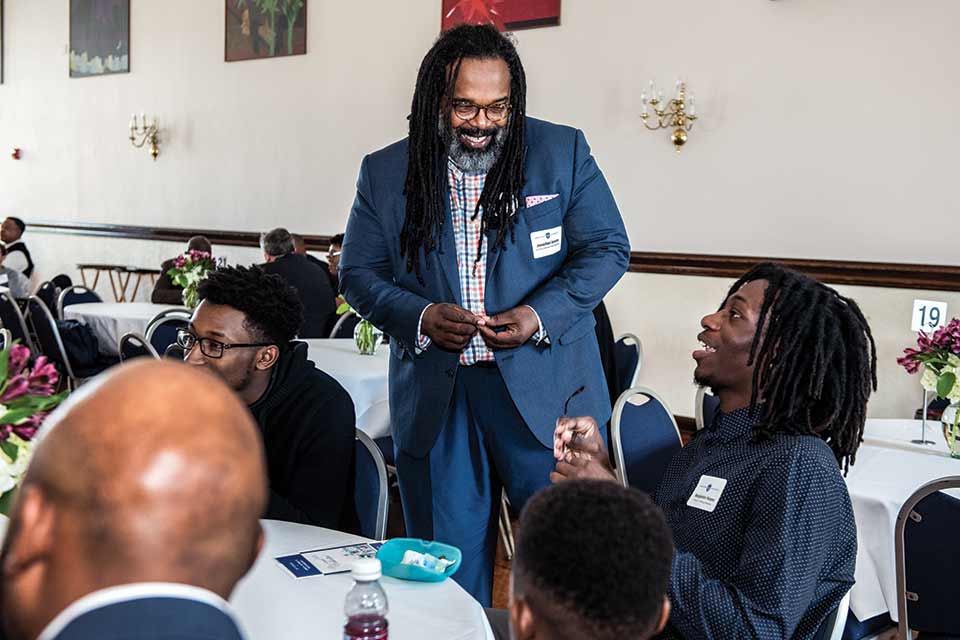 2015 Special Assistant for Diversity Dr. Jonathan Smith smiles as he speaks with a student at an event.