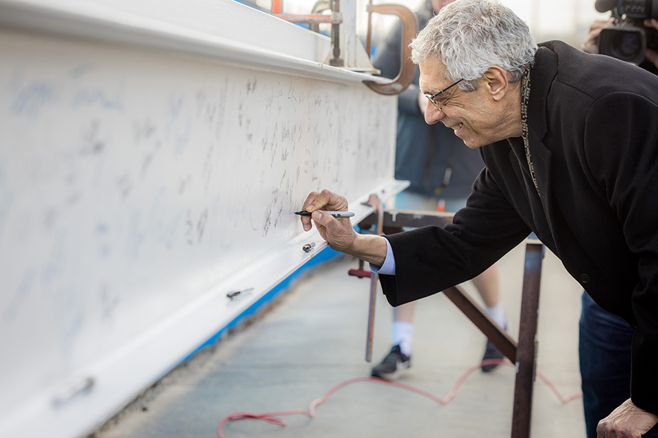 Pestello signs a beam during construction of the O’Loughlin Family Champions Center. Pestello signs a large white beam with a Sharpie during construction of the O’Loughlin Family Champions Center.
